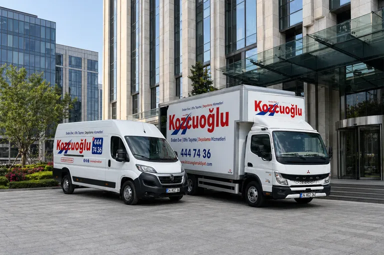 Başakşehir ofis taşıma hizmeti için İstanbul’da modern ofis binası önünde park eden Kozcuoğlu nakliye araçları